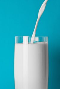 glass-of-milk-against-teal-background